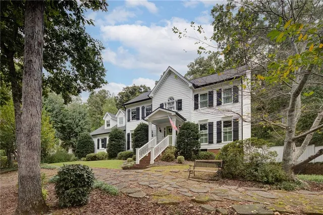 a view of a white house next to a yard with a tree