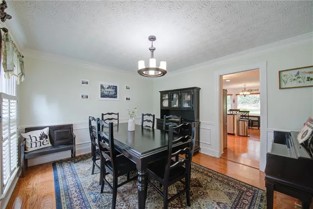 a kitchen with stainless steel appliances granite countertop a refrigerator a stove a sink a dining table and chairs with wooden floor