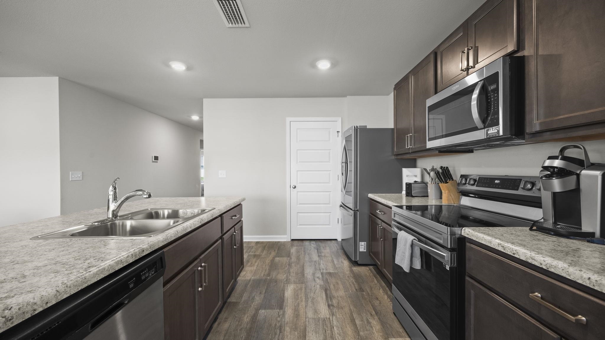 224 Burnston Way Foley, AL 36535 - Photo 16 of 42 Kitchen featuring dark brown cabinets, stainless steel appliances, dark wood finished floors, light countertops, and recessed lighting
