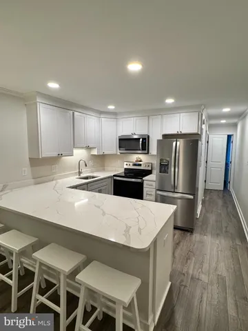 a kitchen with stainless steel appliances a refrigerator a stove a sink a dining table and chairs