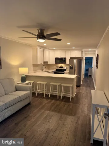 a living room with stainless steel appliances furniture and a wooden floor