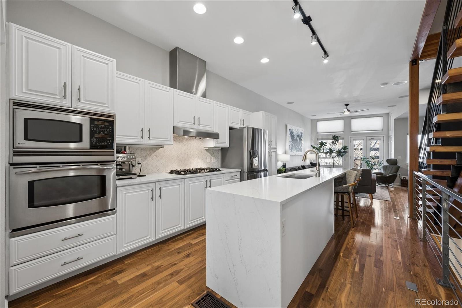 2680 Blake Street, Unit 7 Denver, CO 80205 - Photo 5 of 36 a kitchen with white cabinets stainless steel appliances and wooden floor