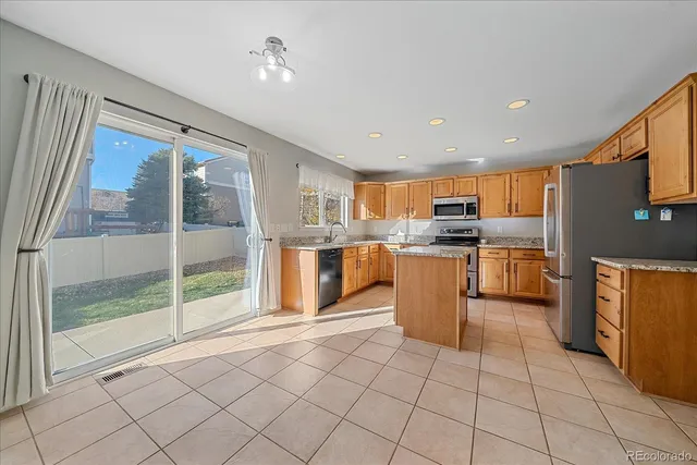 a kitchen with stainless steel appliances granite countertop a refrigerator a sink a stove top oven and cabinets