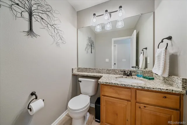 a bathroom with a granite countertop sink toilet and mirror