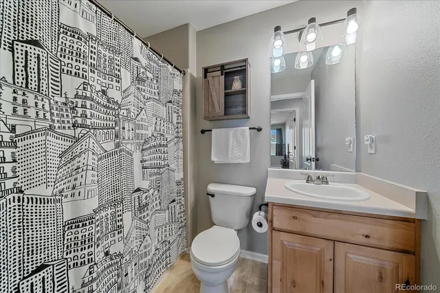 a bathroom with a granite countertop toilet a sink a mirror a lamp and window