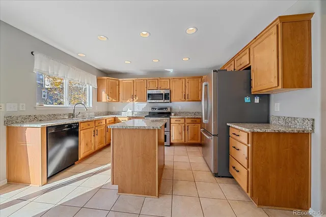 a kitchen with granite countertop a refrigerator stove top oven and sink
