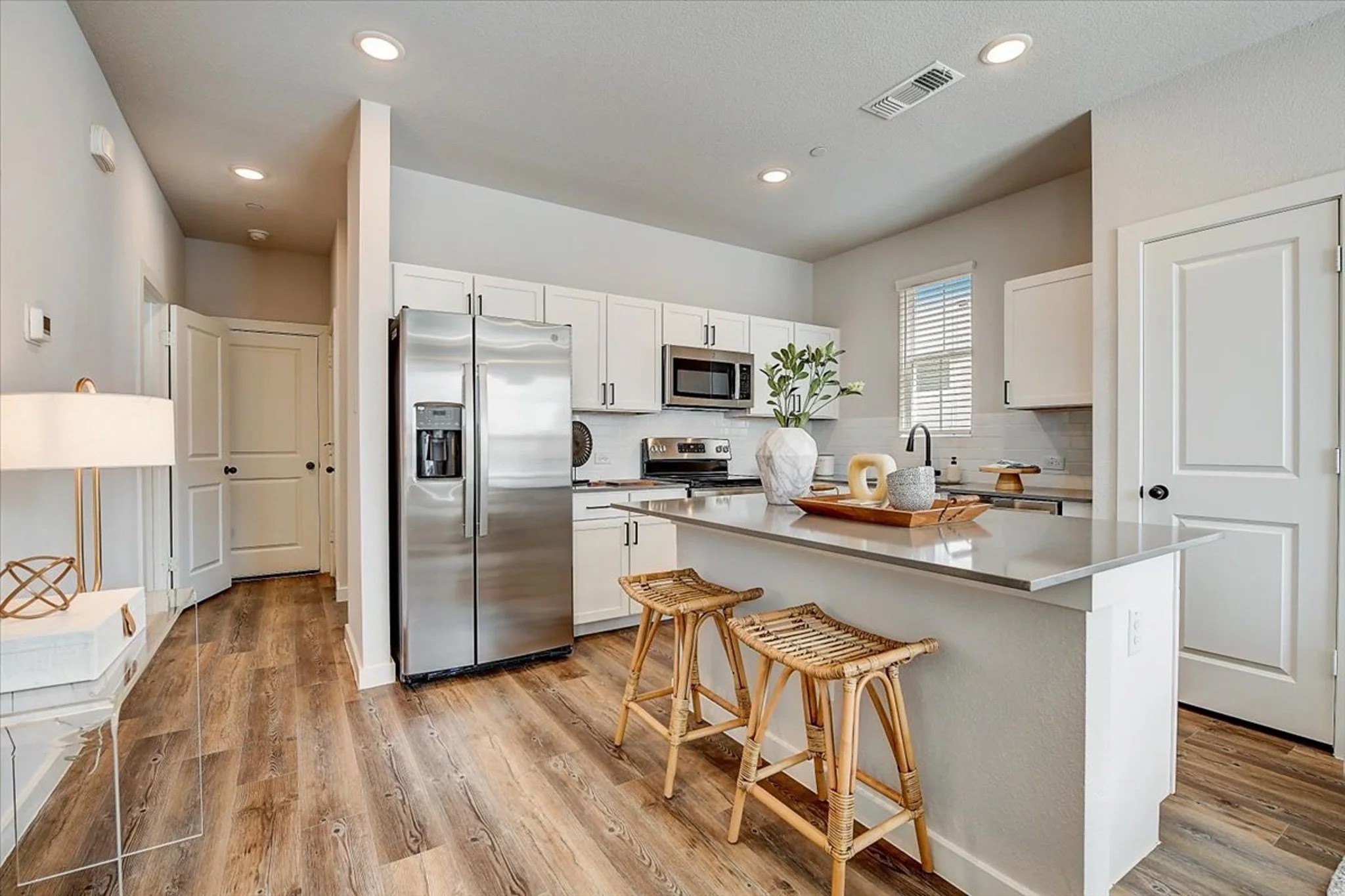 15101 Litsey Crk Drive, Unit 14726R Roanoke, TX 76262 - Photo 13 of 21 a kitchen with stainless steel appliances a microwave a stove a sink dishwasher a refrigerator and white cabinets with wooden floor