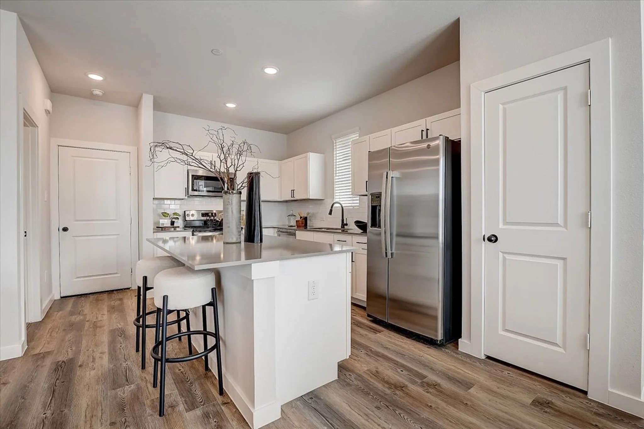 15101 Litsey Crk Drive, Unit 14726R Roanoke, TX 76262 - Photo 6 of 21 a kitchen with kitchen island a refrigerator stove and white cabinets with wooden floor