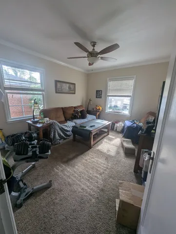 a living room with furniture a large window and gym equipment