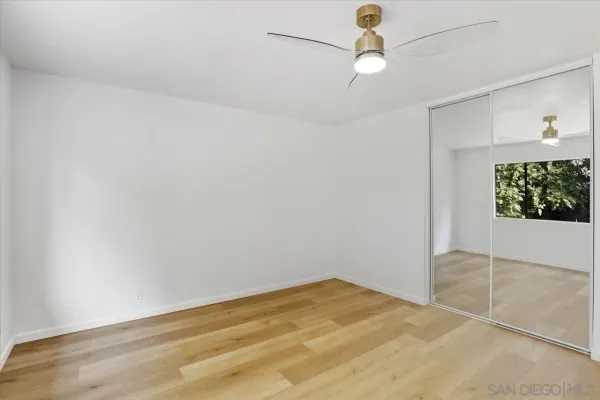 an empty room with windows and fan