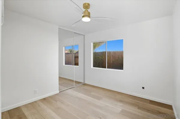 a view of an empty room with chandelier fan