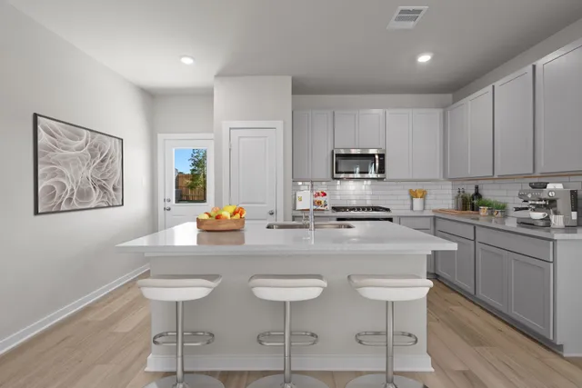 a kitchen with stainless steel appliances granite countertop a sink a stove a refrigerator cabinets and a dining table with wooden floor