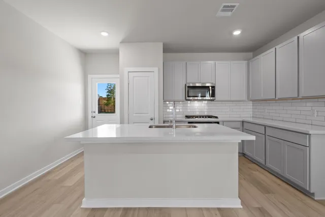 a kitchen with kitchen island sink stove and cabinets