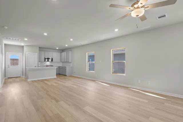 a view of an empty room with a kitchen and a window