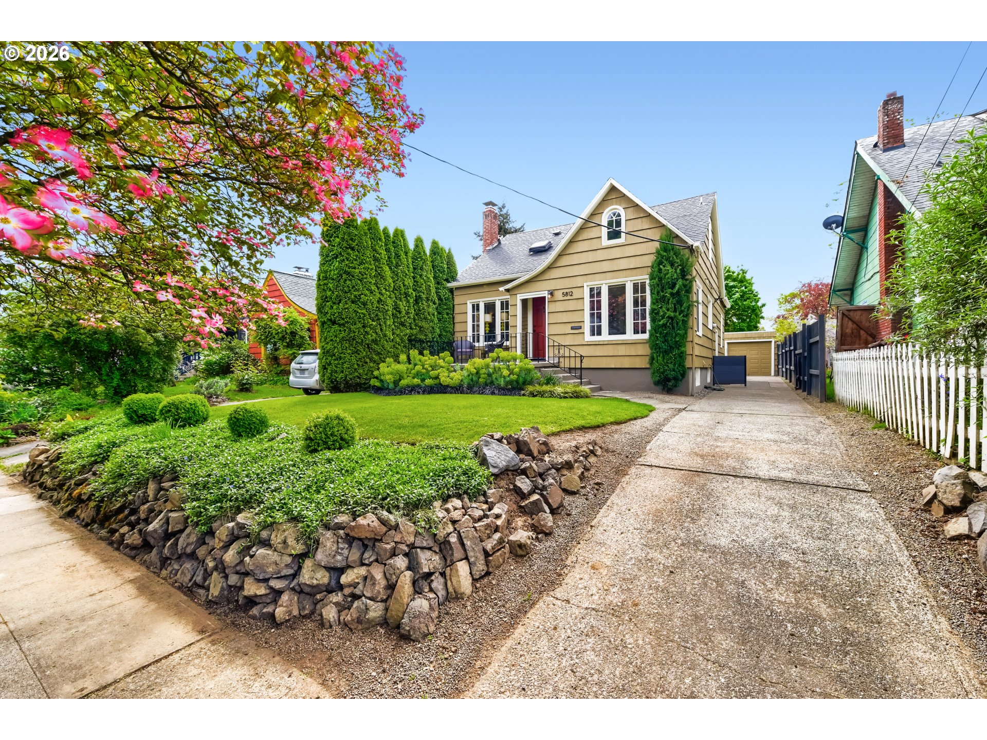 5812 Southeast Bush Street Portland, OR 97206 - Photo 4 of 27 a view of a house with a small yard and flower plants