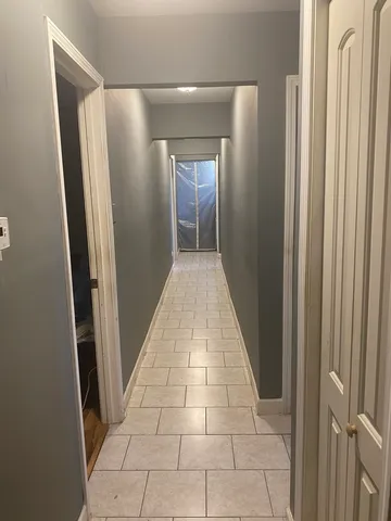 a view of a hallway with wooden floor and a bathroom