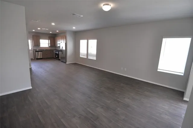 an empty room with wooden floor and windows