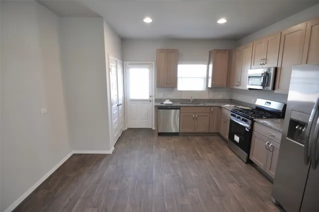 a large kitchen with stainless steel appliances granite countertop a stove a sink dishwasher and a oven with wooden floors