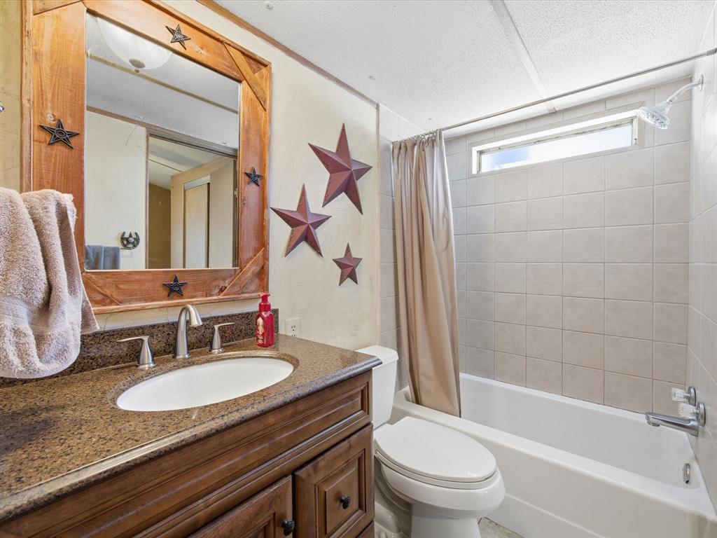 196 Perch Road Bowie, TX 76230 - Photo 21 of 33 a bathroom with a granite countertop sink toilet a mirror and shower