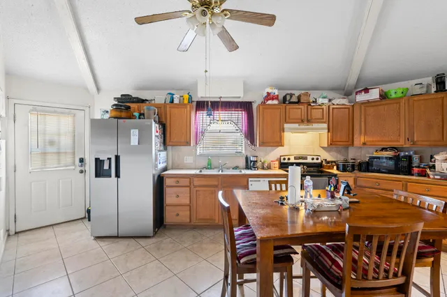 a dining table chairs and a refrigerator in a kitchen