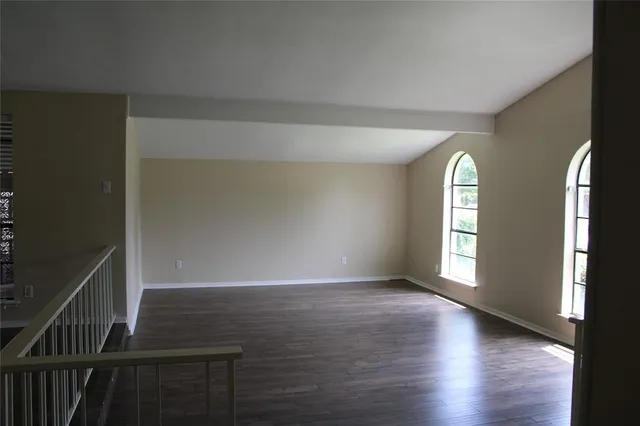 a view of an empty room with window and wooden floor