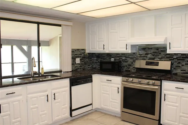 a kitchen with granite countertop white cabinets and white appliances