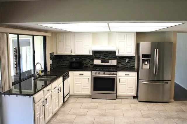 a kitchen with stainless steel appliances granite countertop a stove a sink and a refrigerator