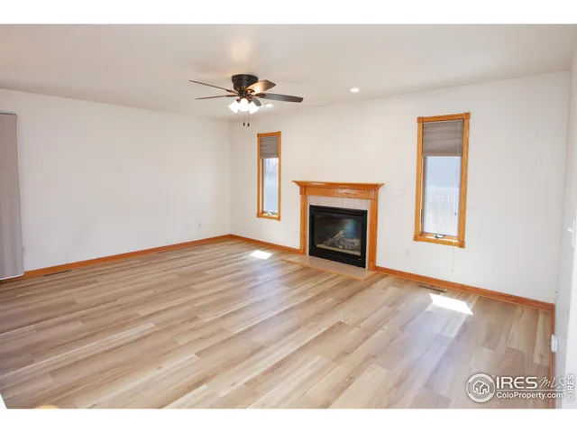 a view of an empty room with wooden floor fireplace and a window