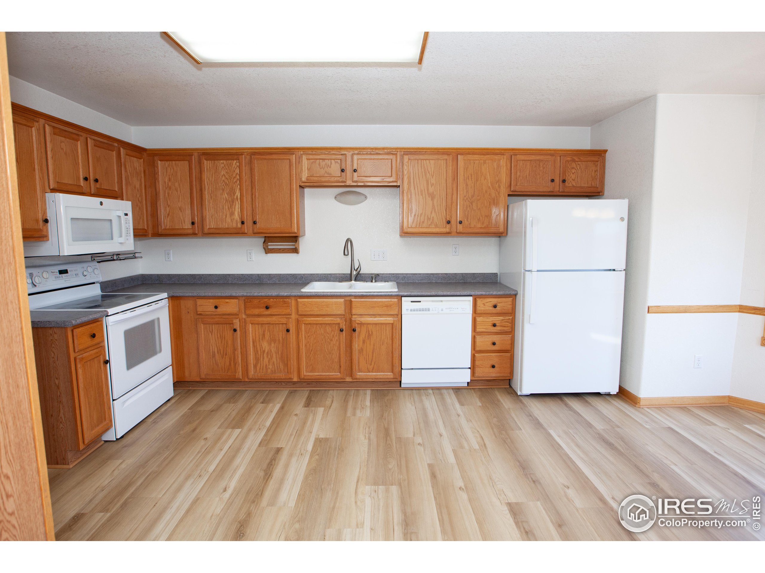 1815 Robin Road Sterling, CO 80751 - Photo 10 of 45 a kitchen with wooden floors and white appliances
