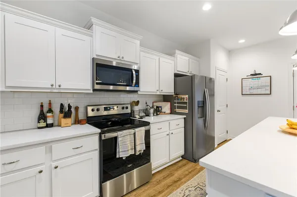 a kitchen with refrigerator a microwave a stove and white cabinets