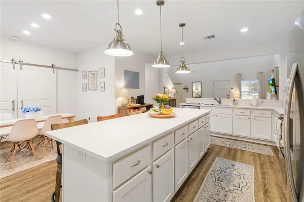 a large white kitchen with a stove a sink a dining table and chairs with wooden floor