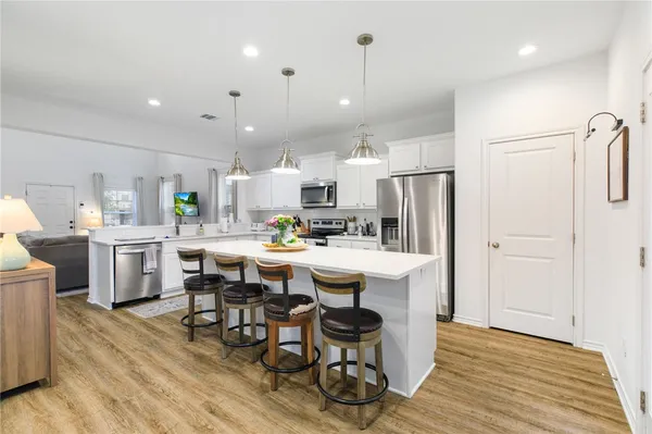 a kitchen with stainless steel appliances a dining table chairs stove refrigerator and cabinets