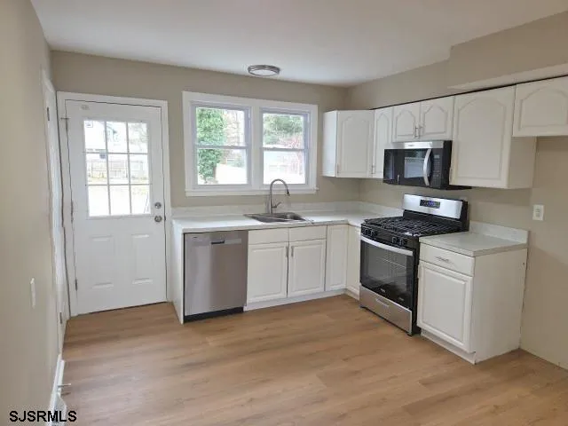 a kitchen with a sink white cabinets and white appliances