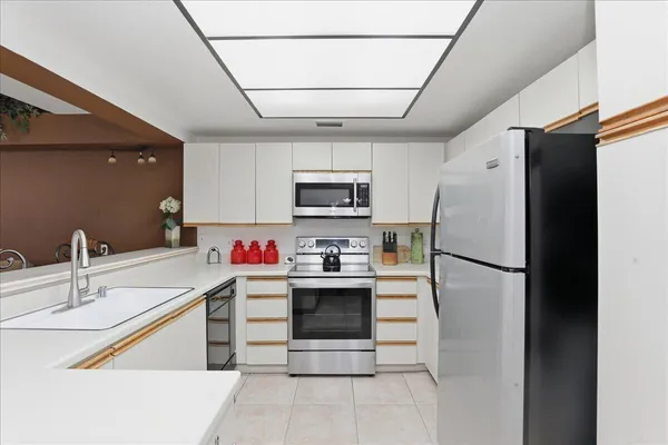 a kitchen with stainless steel appliances a refrigerator sink and white cabinets