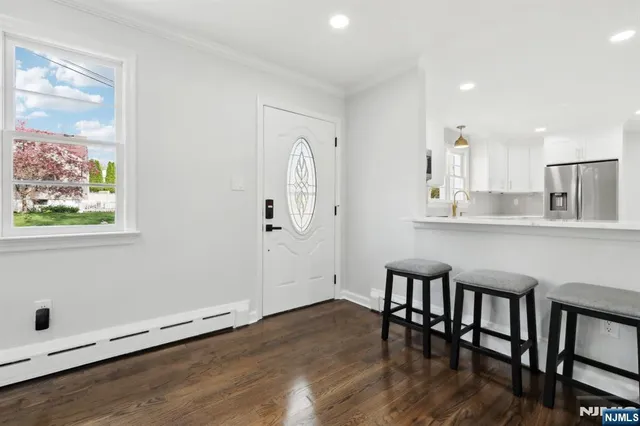 a kitchen with stainless steel appliances granite countertop a stove top oven a sink and white cabinets with wooden floor