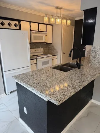 a kitchen with granite countertop a sink a stove and a refrigerator
