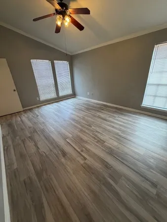 a view of empty room with wooden floor and fan