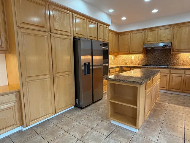 a large kitchen with stainless steel appliances granite countertop a sink a counter space and a view of living room