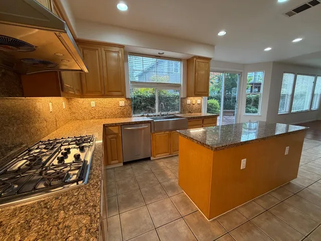 a large kitchen with kitchen island granite countertop a large window and stainless steel appliances