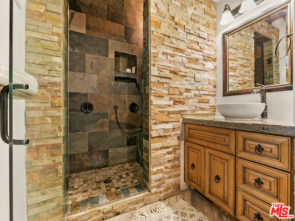 25643 Timpangos Drive Monte Nido, CA 91302 - Photo 21 of 24 a bathroom with a granite countertop sink a toilet and shower