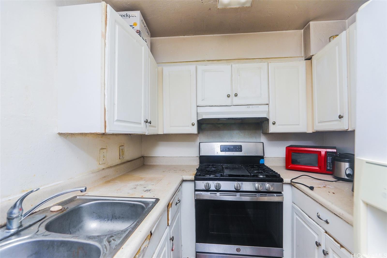 87-122 Helelua Street, Unit C103 Waianae, HI 96792 - Photo 3 of 12 a kitchen with granite countertop a sink a stove and cabinets