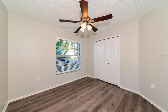 a view of an empty room with window and wooden floor