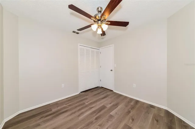 an empty room with wooden floor and ceiling fan
