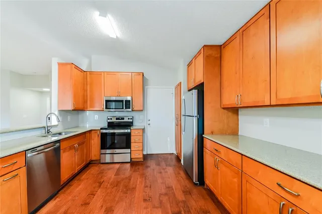 a kitchen with stainless steel appliances a sink cabinets and a large window