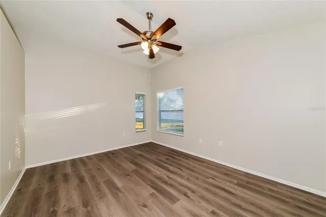 an empty room with a window and ceiling fan