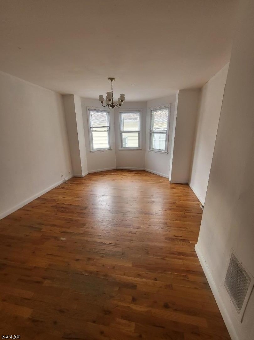 129 Sayre Street Elizabeth, NJ 07208 - Photo 4 of 5 a view of an empty room with window and wooden floor