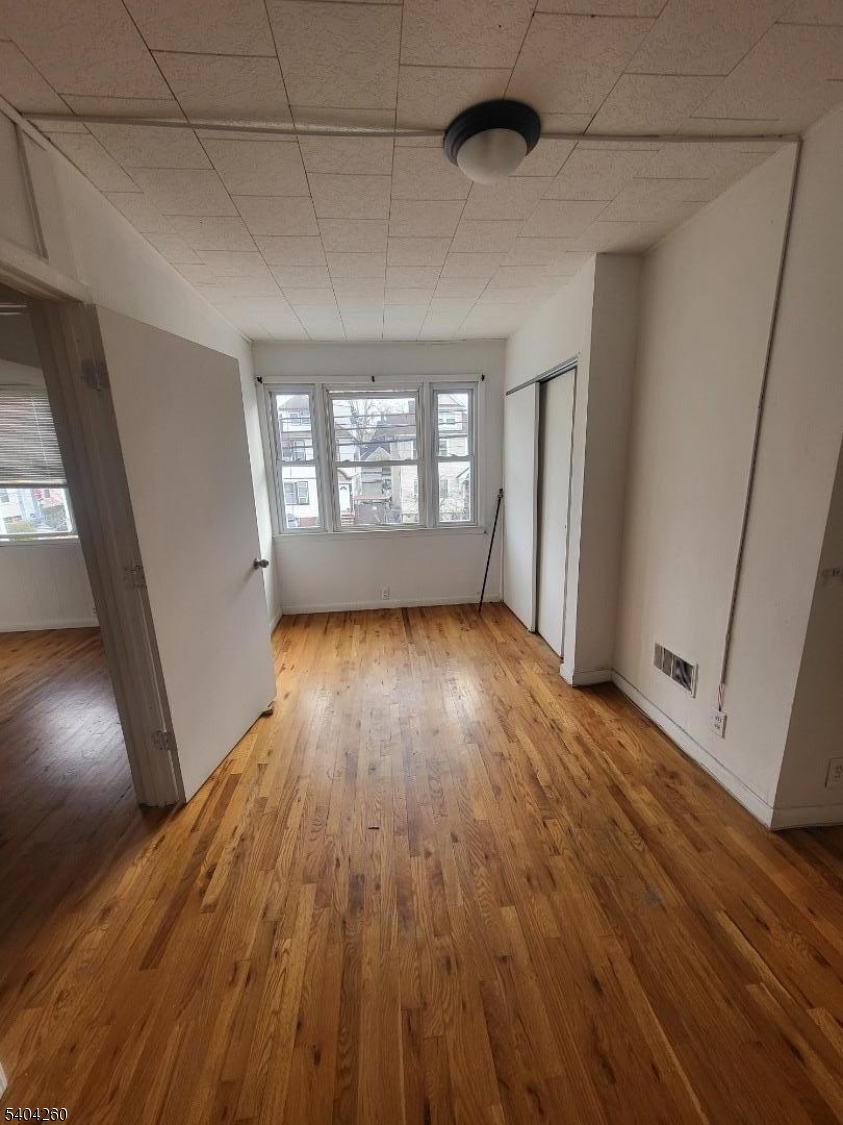 129 Sayre Street Elizabeth, NJ 07208 - Photo 5 of 5 an empty room with wooden floor and windows