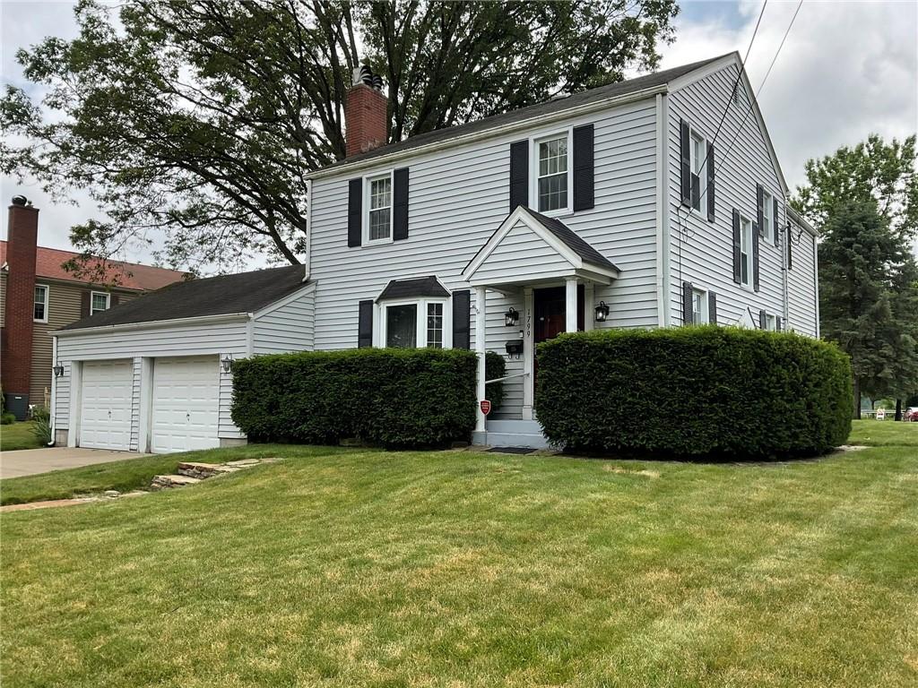 a view of a house with a yard and large trees