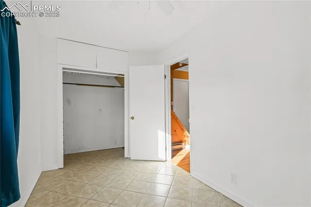 a view of an empty room with window and chandelier fan