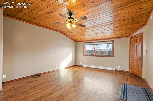 an empty room with wooden floor chandelier fan and windows